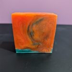 Square soap bar with a mix of orange and green swirling together.