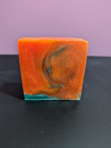 Square soap bar with a mix of orange and green swirling together.