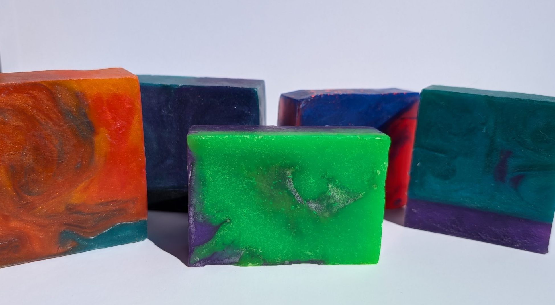 5 Nirvanya Handcrafted Soaps. 1st Orange and Green Swirl. 2nd Purple, Green and Black Swirl. 3rd Green and Purple Mix, 4th Blue and Red Swirl. 5th Purple, Blue and Green swirl.