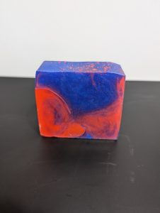Square soap bar with a mix of blue and red swirling together.